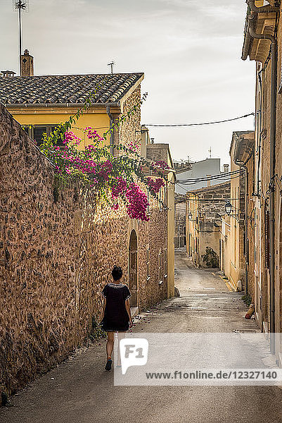 Woman walking down a narrow street; Alcudia  Mallorca  Balearic Islands  Spain