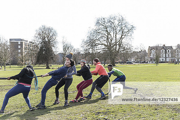 Determined team pulling rope in tug-of-war in park