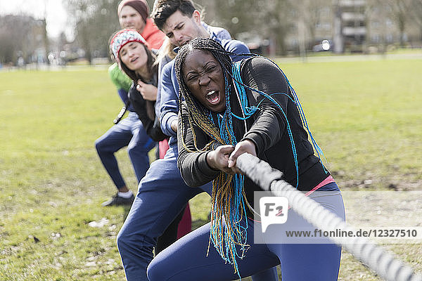 Determined team pulling rope in tug-of-war at park