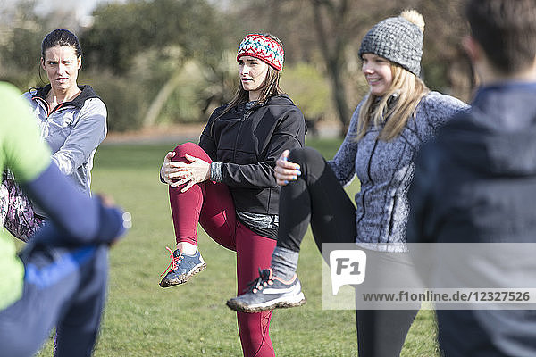 Women exercising  stretching in sunny park