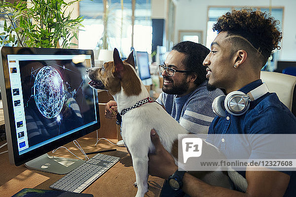 Graphic designers with dog working at computer in office