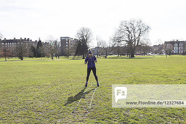 Woman exercising  doing speed ladder drill in sunny park