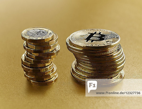 Golden Bitcoins stacked next to British pound coins