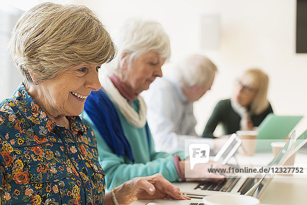 Senior women using laptops in conference room meeting