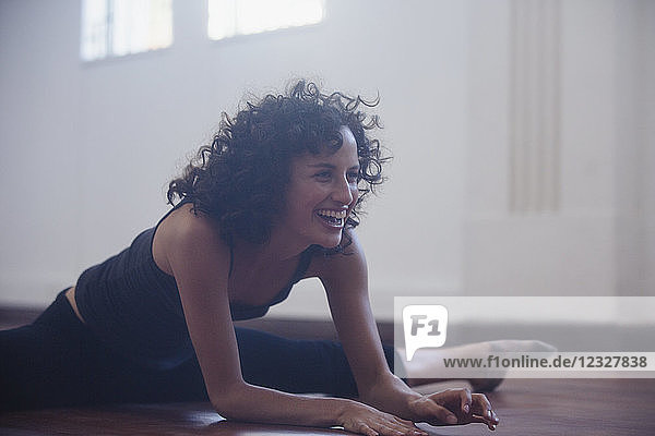 Glückliche  selbstbewusste junge Tänzerin beim Stretching im Tanzstudio