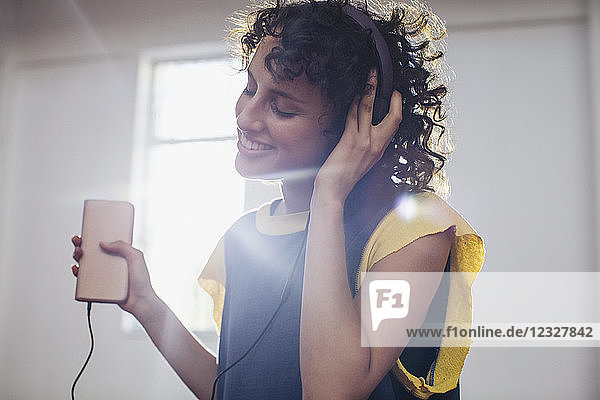 Smiling carefree young woman listening to music with headphones and mp3 player