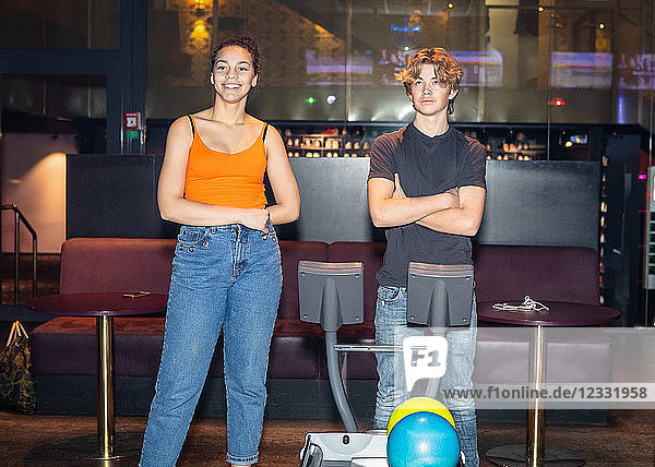 Multi-ethnic friends standing by computer at bowling alley