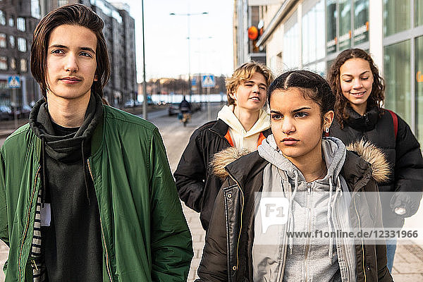 Multi-ethnic teenagers walking on sidewalk in city