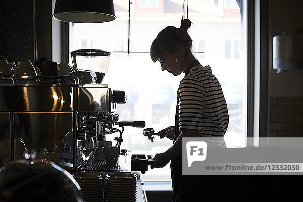Female barista using coffee filter at cafe