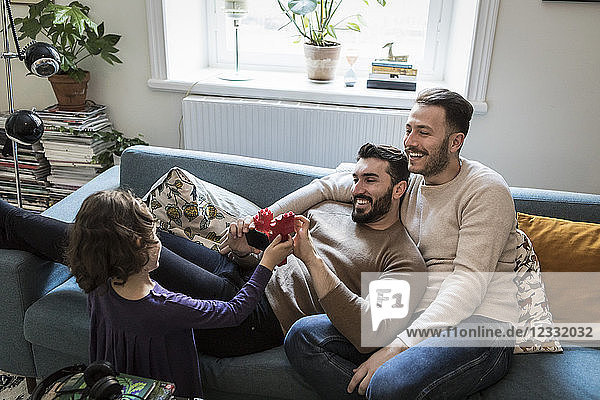 High angle view of daughter showing blocks to smiling fathers in living room