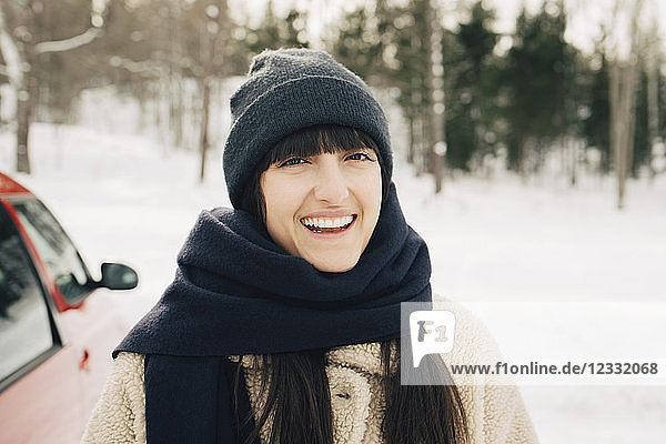 Portrait of smiling woman wearing scarf on snowy landscape