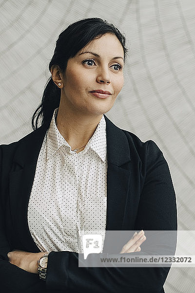 Thoughtful confidence businesswoman standing against wall at office