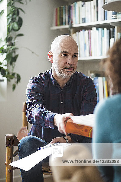 Male therapist giving tissue to female patient during therapy session