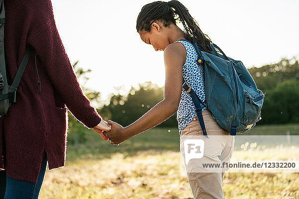 Midsection of woman holding hands with daughter while hiking at park