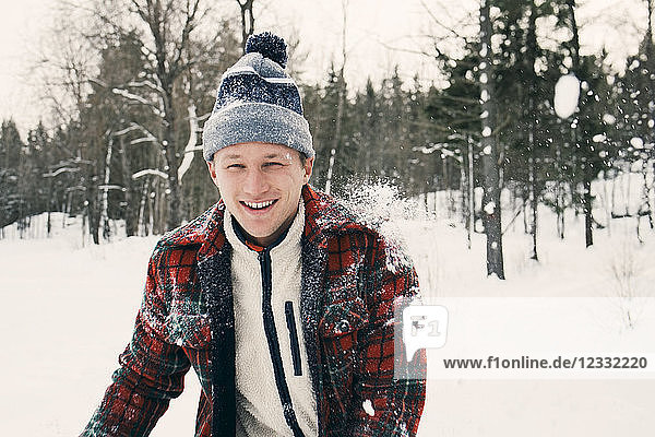 Portrait of happy mid adult man in warm clothing on snow covered field