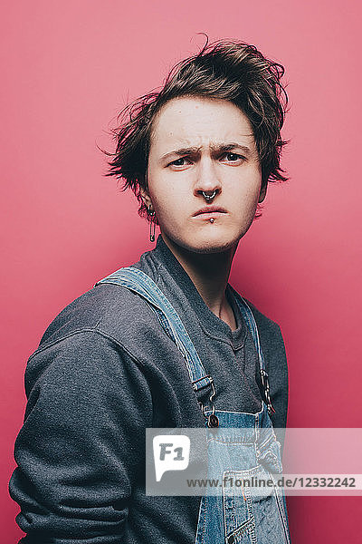 Trendy young man looking suspiciously over pink background