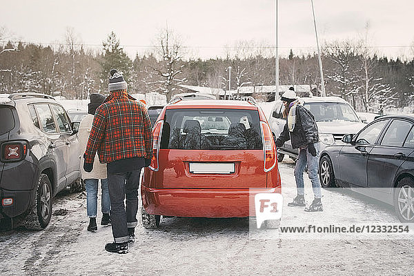 Friends walking towards car at parking lot during winter