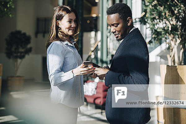 Businesswoman showing mobile phone to male colleague during conference