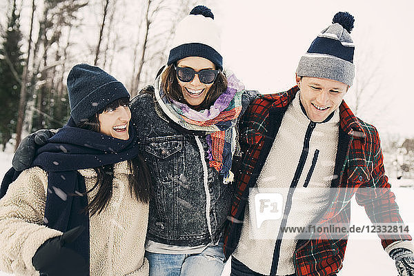 Cheerful male and female friends enjoying at park during winter