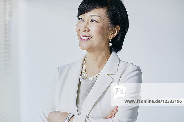 Japanese senior businesswoman against white wall