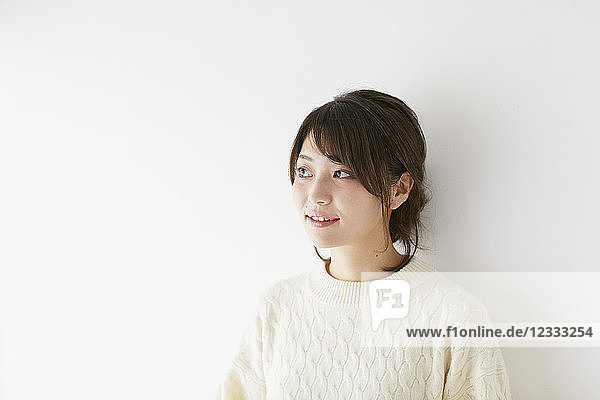 Junge japanische Frau vor weißer Wand