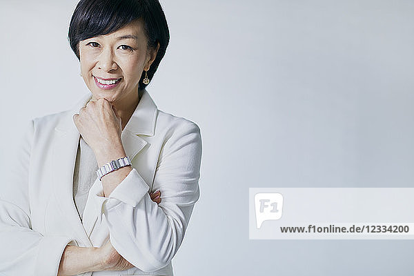 Japanese senior businesswoman against white wall