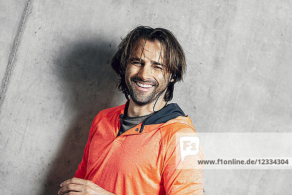 Portrait of smiling athlete at concrete wall