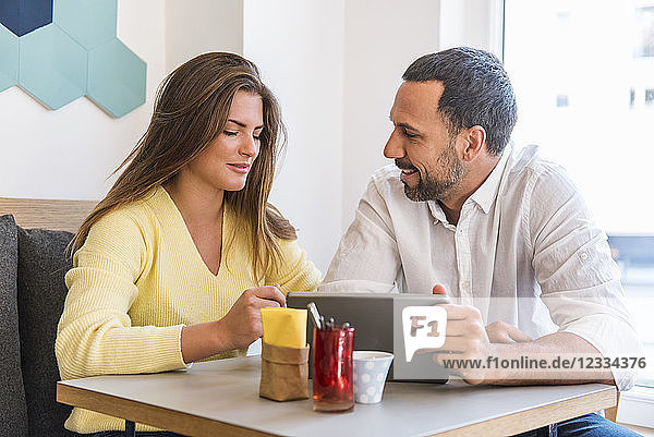 Young woman and man sharing tablet in a cafe