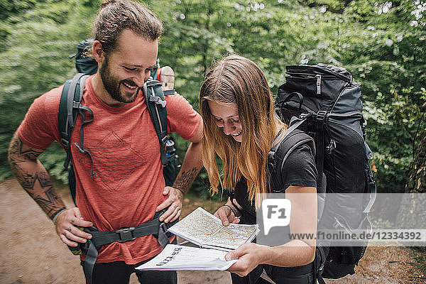 Happy young couple on a hiking trip reading map