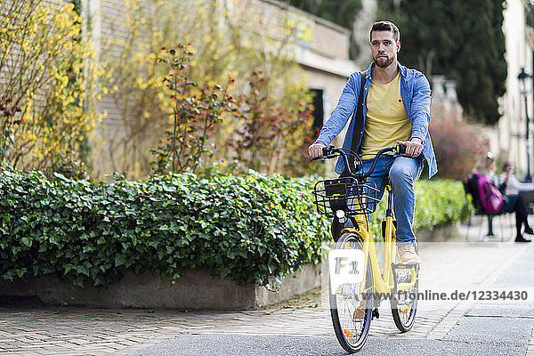 Young man riding rental bike in the city