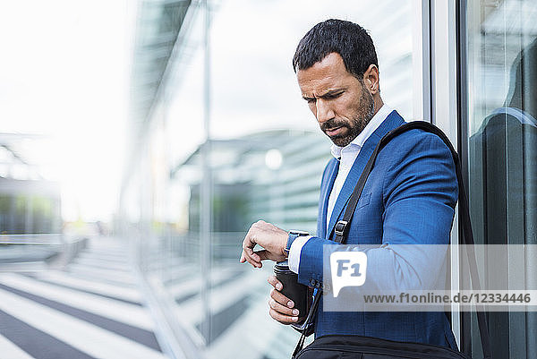 Businessman with cup of coffee  looking on his watch
