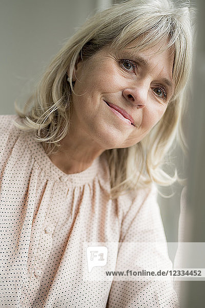 Portrait of smiling mature woman leaning against windowpane