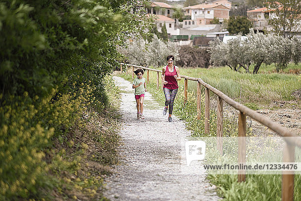 Mother and daughter running on a path in nature enviroment