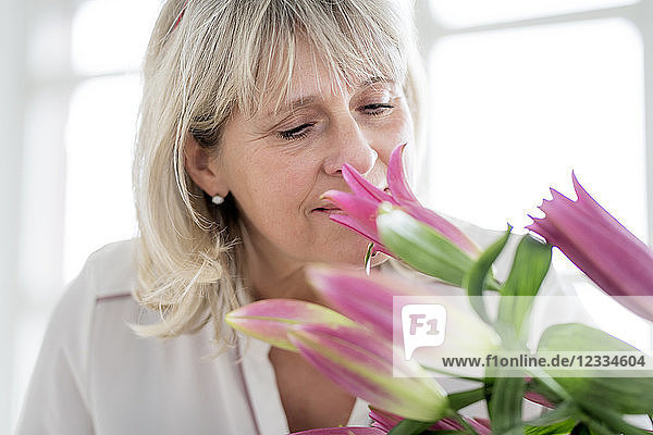 Mature woman smelling at bunch of flowers