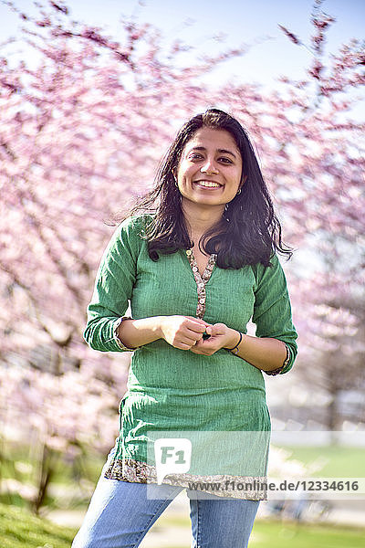 Portrait of happy young woman in a park at cherry blossom tree