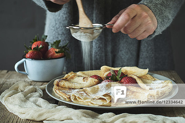 Woman preparing pancakes with strawberries for breakfast
