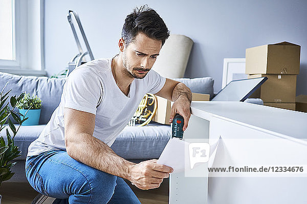 Man reading instructions while assembling furniture in new apartment