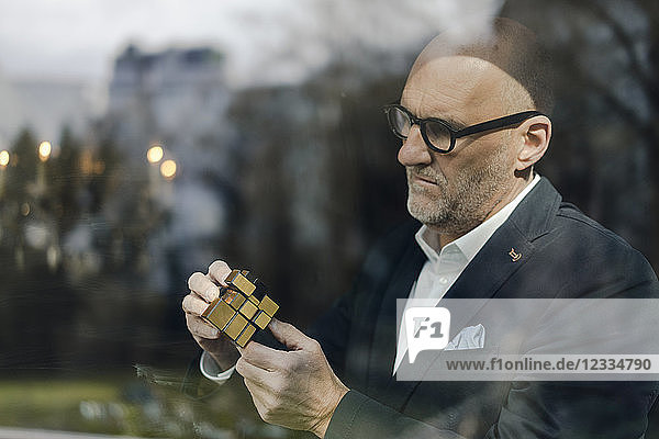 Senior businessman putting together puzzle cube