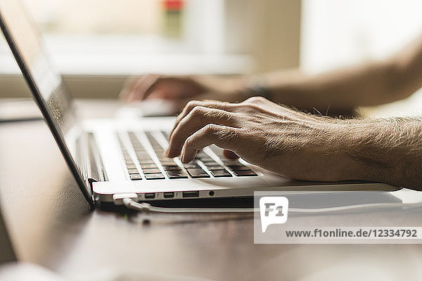 Man's hand on keyboard of laptop  partial view