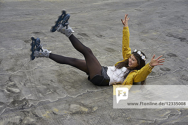 Smiling woman with inline skates falling on ground