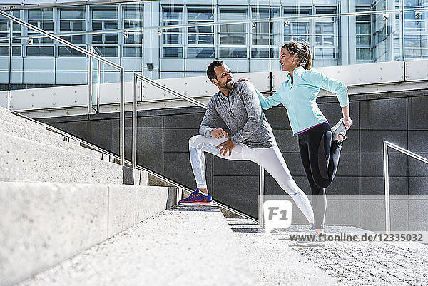 Couple doing stretching exercise on stairs in the city