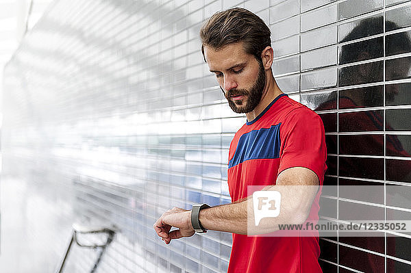 Man having a break from running checking the time on a smartwatch