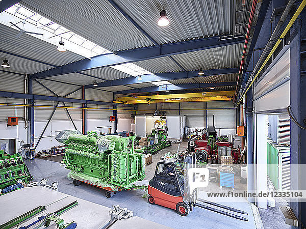 Fork-lift driver pulling gas engine out of factory shop floor