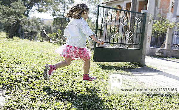 Little girl running on meadow in the garden