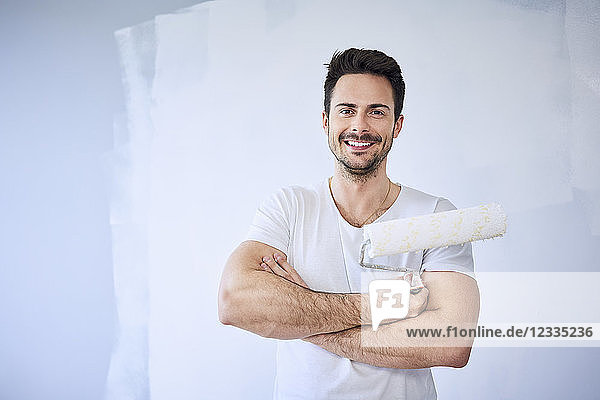 Portrait of smiling man painting wall in apartment