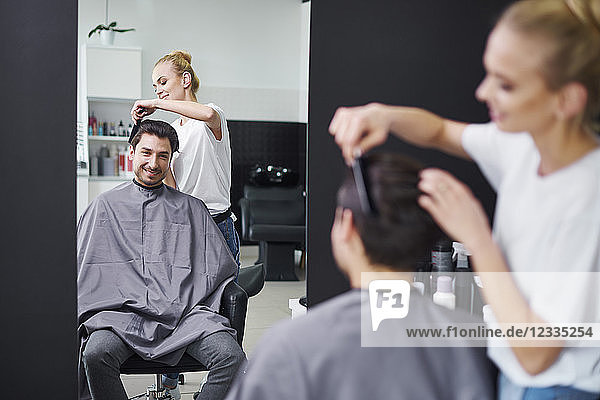 Smiling hairdresser combing man's hair