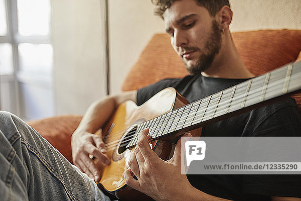 Man playing guitar on couch
