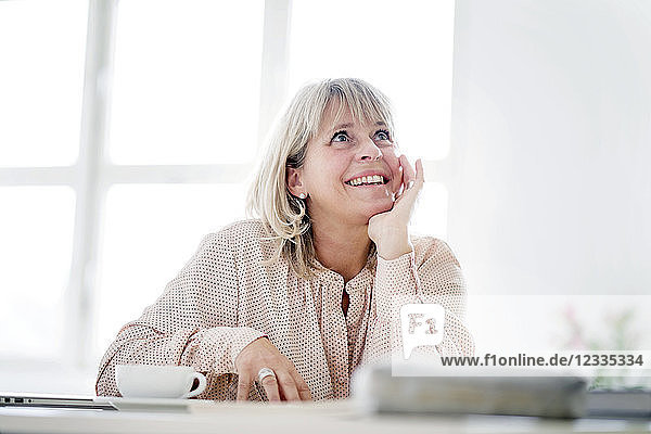 Smiling mature businesswoman at desk looking up