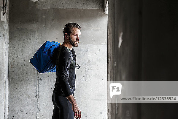 Athlete holding bag at concrete wall