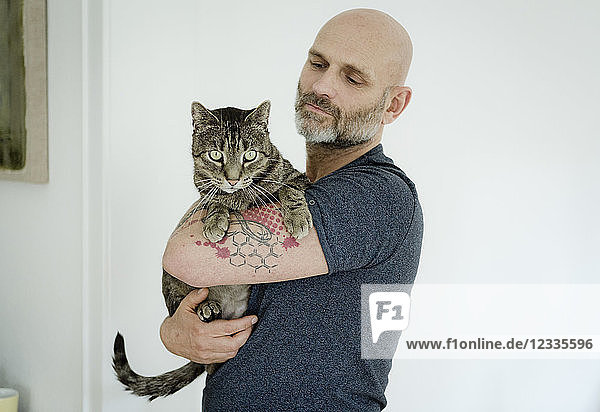 Tattooed man carrying his cat